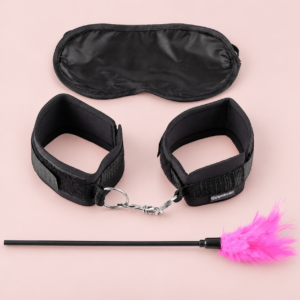 Sensual Seduction bondageset med svart ögonmask, handledsbojor och rosa fjäder på rosa bakgrund
